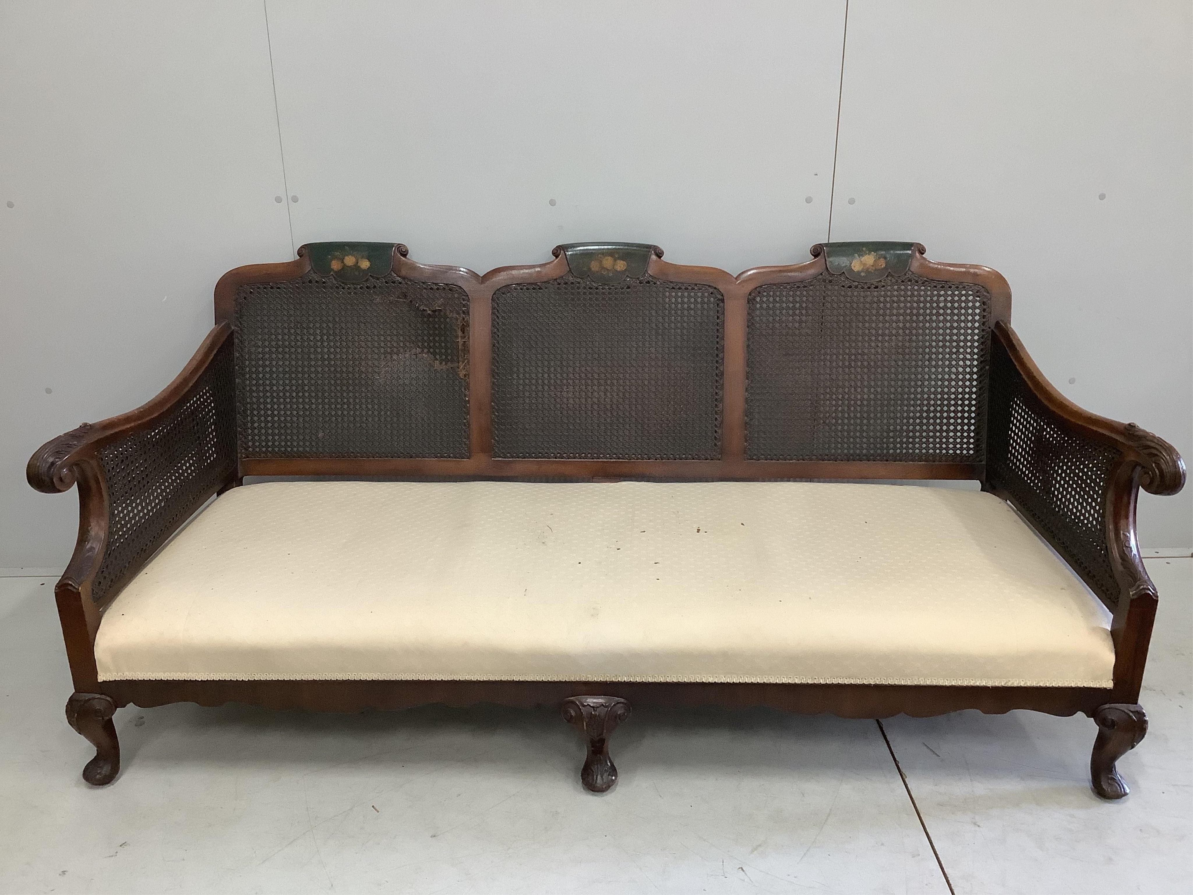 An early 20th century part painted walnut three piece bergere suite, settee width 186cm, depth 78cm, height 80cm. Condition - fair, although one cane panel is damaged and needs repair